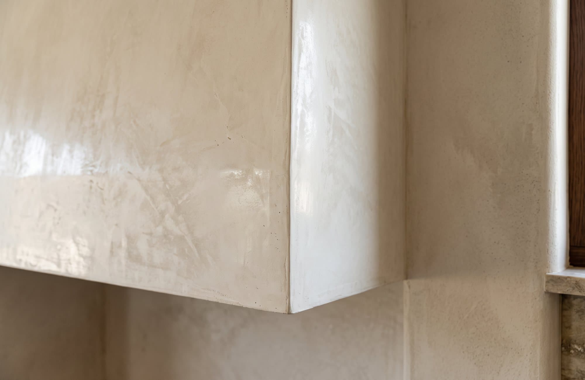 Close-up of the polished plaster edge of the hood meeting the limewash wall