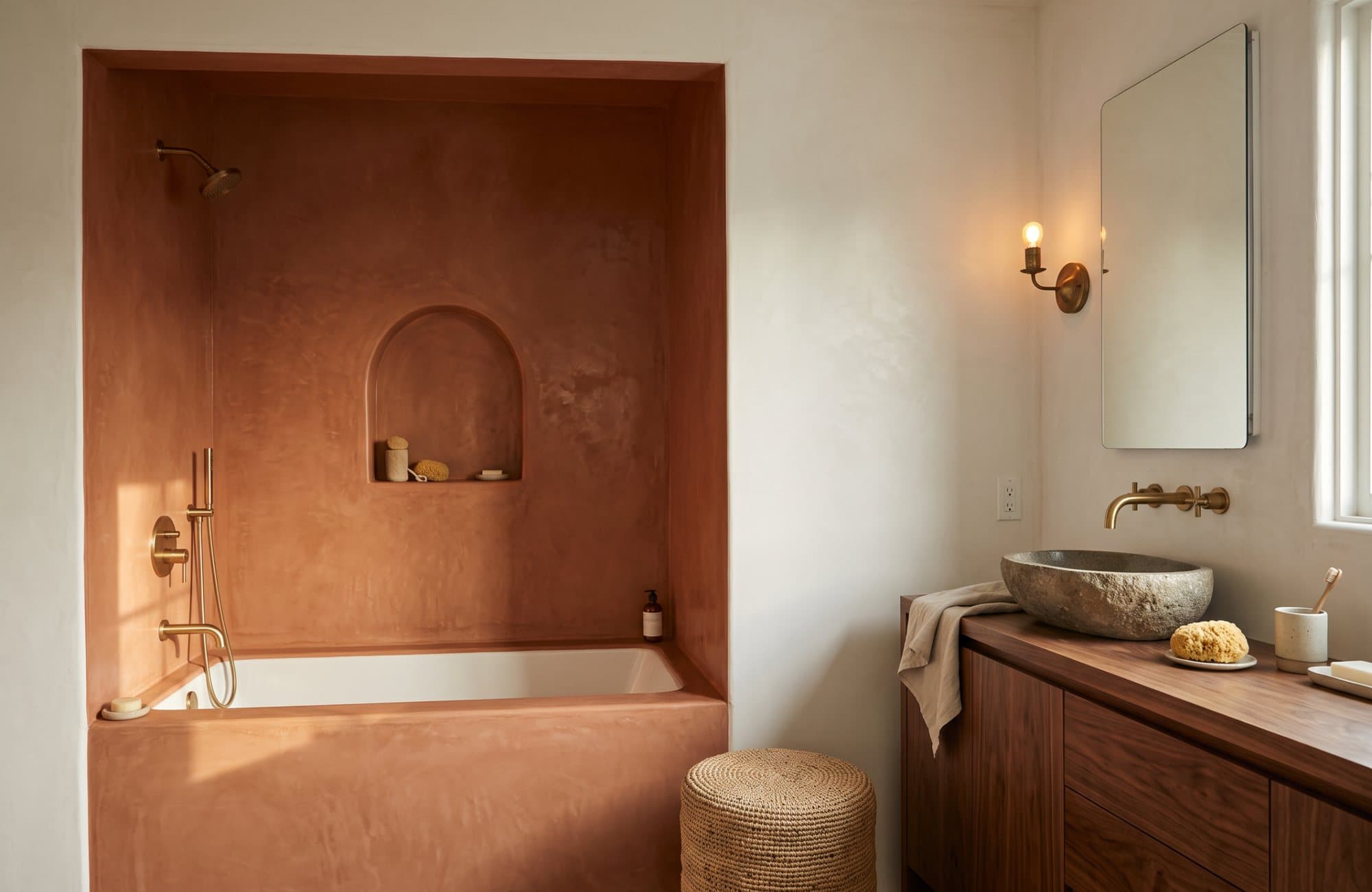 The tadelakt tub alcove with pale marmorino walls and a stone basin on a walnut vanity