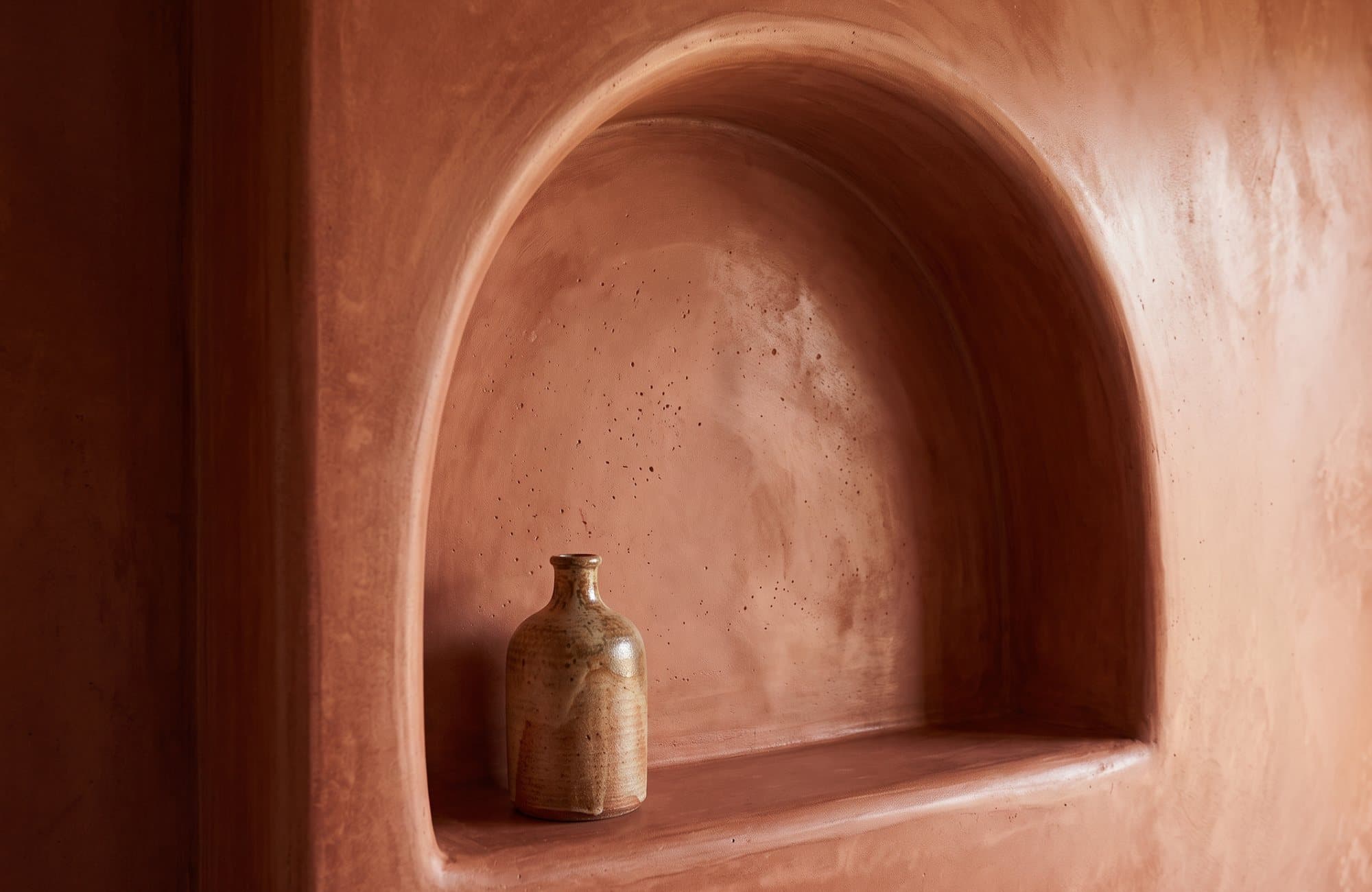 Close-up of the arched tadelakt niche, polished inside the curve without a seam